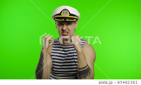 Young sailor man is angry and shows fists. Seaman guy in sailor's vest Young sailor man is angry and shows fists. Seaman guy in sailor's vest 65482161