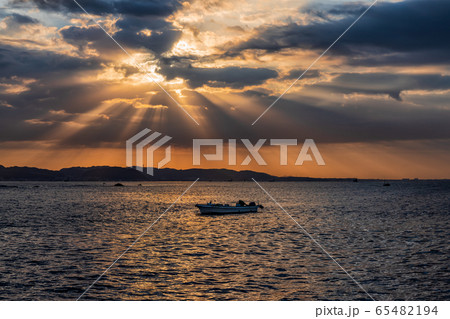 朝焼けの空の薄明光線に照らされる美しい雲と海面 65482194