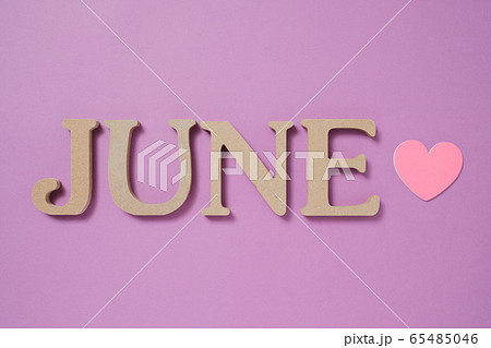 紫色の背景に置かれた「JUNE」のアルファベットブロックとピンクのハート 65485046
