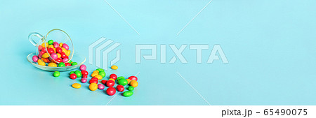 Colored glazed candy beans. Glass mug on saucer Colored glazed candy beans. Glass mug on saucer 65490075