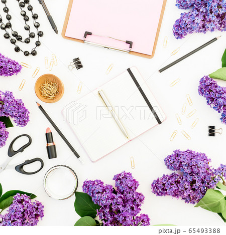 Freelancer workspace with diary, lipstick, scissors, branches of lilac and accessories on white. 65493388