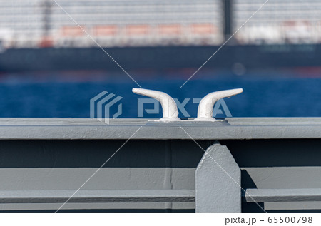 White cleat welding on the grey hull of the warship sailing along side a passenger ship 65500798