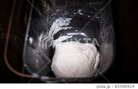 Dough in bread pan of autimatic breadmaker for home use. Not raised dough preparing for baking in smart bread maker machine loaf-pan. 65500914