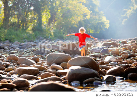 Child hiking in mountains. Kids at river shore. 65501815
