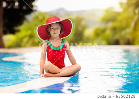Child with hat in swimming pool. Tropical vacation 65502129