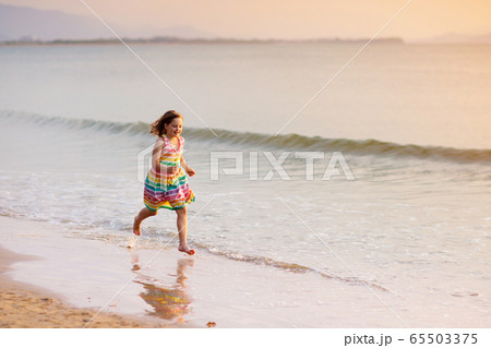 Child playing on ocean beach. Kid at sunset sea. Child playing on ocean beach. Kid at sunset sea. 65503375