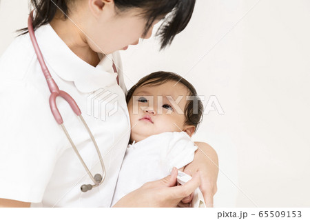 愛児用を持ち赤ちゃんを抱き検温をする看護師イメージの写真素材