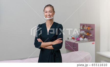 Cosmetology cabinet. Beautician stands in mask and Cosmetology cabinet. Beautician stands in mask and 65511610