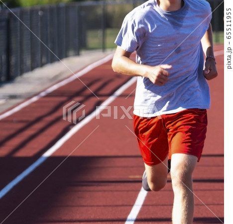 Front view of runner on red track up close Front view of runner on red track up close 65511955
