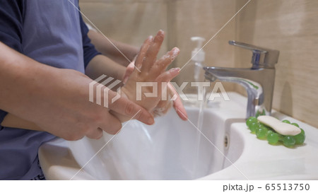 Mom supports the hands of her son showing how to properly wash. Family washing hands together. Hygiene concept 65513750