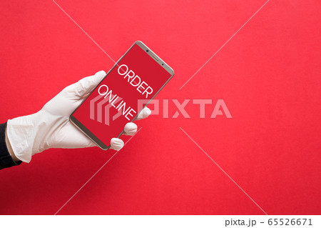 Hand in white protective glove holding smartphone with text Order Online 65526671