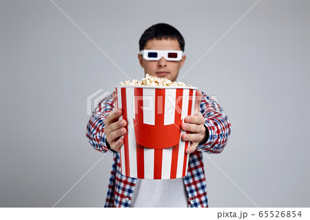 man in red-blue 3d glasses showing popcorn bucket man in red-blue 3d glasses showing popcorn bucket 65526854