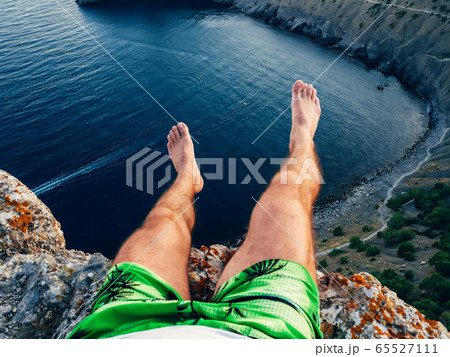 feet tourist sitting on top of the mountain against the sea 65527111