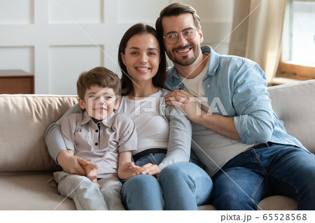 Portrait of happy young family relaxing on sofa together 65528568