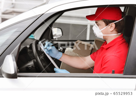 Fast delivery with courier at home. Man in car checks data to boxes 65529953
