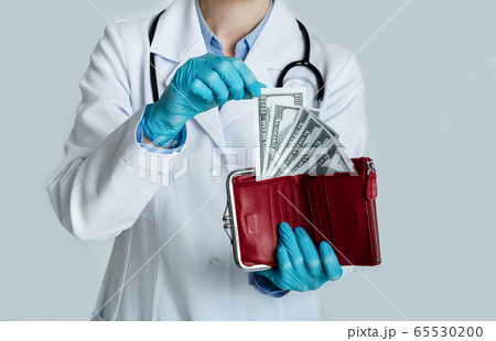 Doctor in white coat holds red purse with dollars in hands and takes money 65530200
