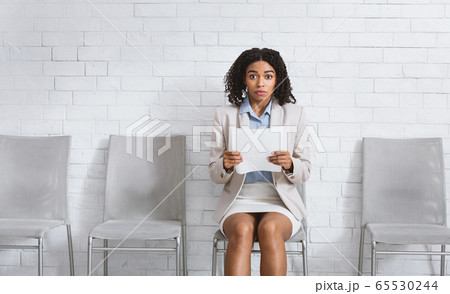 Beautuful black girl with resume being afraid of her employment interview in office. Space for text Beautuful black girl with resume being afraid of her employment interview in office. Space for text 65530244