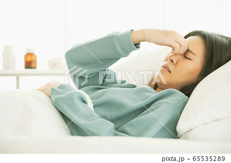 若い　女性　病気　体調　悪い　ベッド　寝込み　咳　薬　休み　人物　素材 65535289