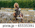Young blond girl sitting at table in public park 65535391