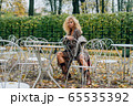 Young blond girl sitting at table in public park 65535392