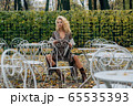 Young blond girl sitting at table in public park 65535393