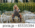 Young blond girl sitting at table in public park 65535394