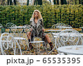 Young blond girl sitting at table in public park 65535395