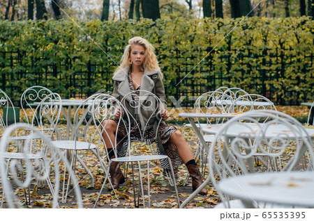 Young blond girl sitting at table in public park Young blond girl sitting at table in public park 65535395
