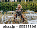 Young blond girl sitting at table in public park 65535396