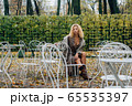 Young blond girl sitting at table in public park 65535397