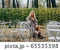 Young blond girl sitting at table in public park 65535398