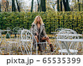 Young blond girl sitting at table in public park 65535399
