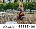 Young blond girl sitting at table in public park 65535400