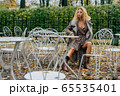 Young blond girl sitting at table in public park 65535401