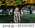 Young blond girl walking in public park in fall 65535403
