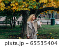 Young blond girl walking in public park in fall 65535404