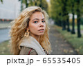 Young blond girl walking in public park in fall 65535405