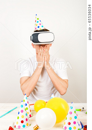 Young man wearing virtual reality glasses sits in 65536034