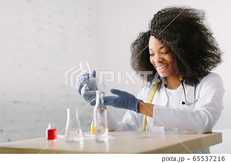 Young beautiful African American girl female with glass equipment in the lab Researcher researching in the laboratory Young beautiful African American girl female with glass equipment in the lab Researcher researching in the laboratory 65537216