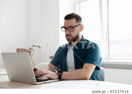 Confident bearded businessman typing on keyboard using laptop. 65537414