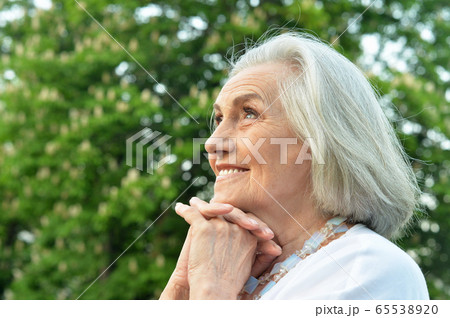 Portrait of senior beautiful smiling woman posing in spring park Portrait of senior beautiful smiling woman posing in spring park 65538920