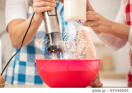 Detail of two females putting flour into a red Detail of two females putting flour into a red 65540003