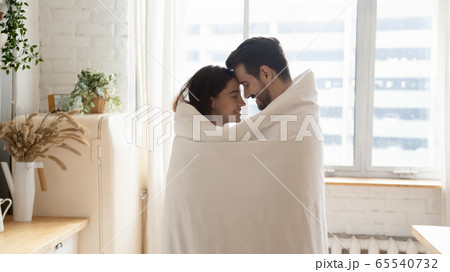 Loving couple wrapped in cover having romantic moment at home 65540732