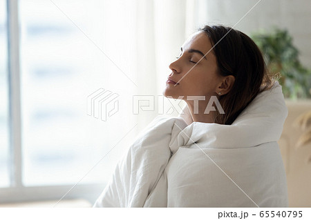 Young woman relax ta home warming up in blanket 65540795