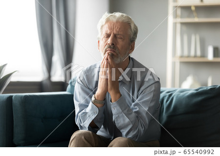 Faithful older middle aged man praying begging God. 65540992