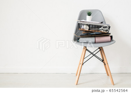 Grey plastic office chair with folded textile samples and basket with supplies 65542564