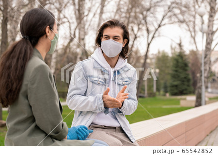 Young man and his girlfriend in protective masks discussing something Young man and his girlfriend in protective masks discussing something 65542852