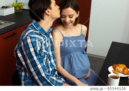Caring young man kissing pregnant woman in forehead Caring young man kissing pregnant woman in forehead 65544126