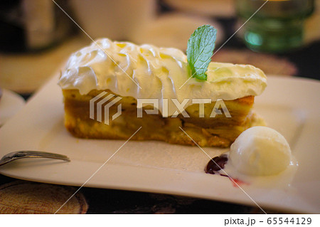 Warm apple pie covered in whipped cream with a 65544129