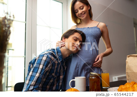 Caring man embracing pregnant woman during breakfast Caring man embracing pregnant woman during breakfast 65544217